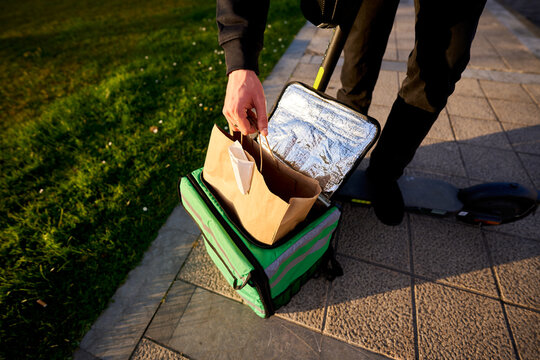 Food delivery service courier packing meal in thermal bag