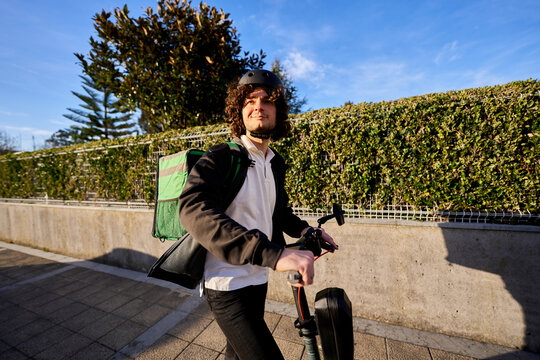 Food delivery courier riding electric scooter in city