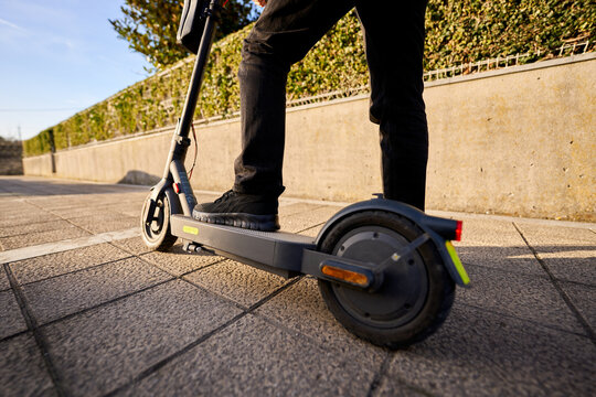 Person riding electric scooter on city sidewalk