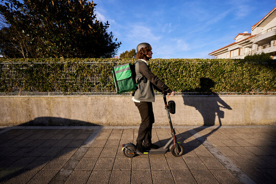 Food delivery courier riding electric scooter in city