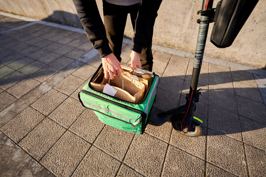 Food delivery courier packing takeaway meal in thermal bag