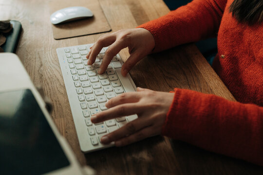 Close Up of Hands Typing on Keyboard at Wooden Desk