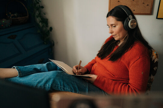 Female Remote Worker Writing in Notebook at Desk