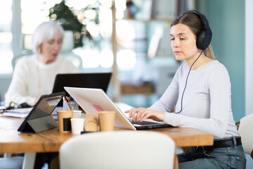 Fototapeta premium Two businesswomen work on laptops in a modern company office
