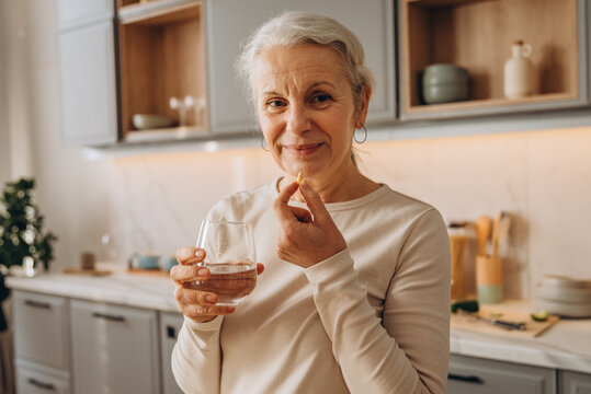 Portrait of positive senior lady takes medical supplements for health care at home
