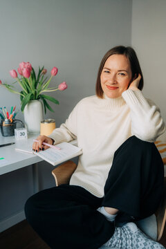 Smiling Woman with Notebook in Cozy Home Office
