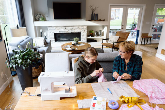 Grandma and granddaughter sewing together at home