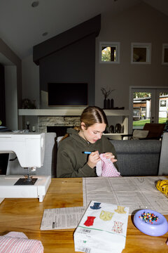 Teen sewing at home on a pink fabric project