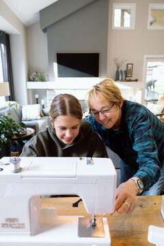 Grandmateaching granddaughter to sew