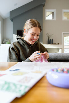 Smiling teen sewing a fabric project at home