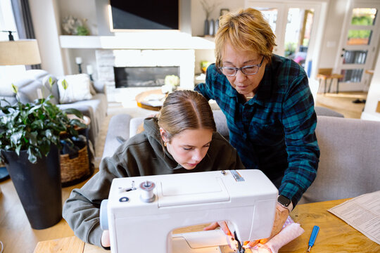 Grandmother teaching granddaughter on a machine at home