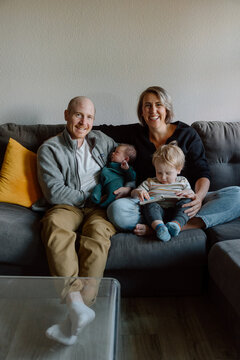 Candid family portrait of parents and young children on a cozy c