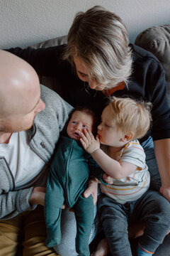 Parents cuddling newborn with toddler sibling in candid family m