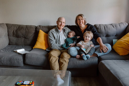 Candid family of parents with baby and toddler on couch