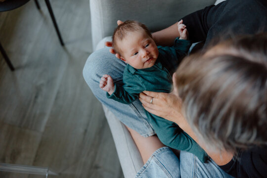 Parent holding newborn baby on lap, candid family moment