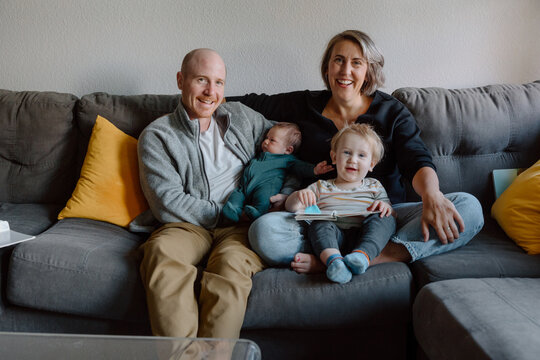Candid family portrait of parents with toddler and newborn on co
