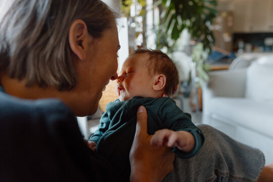 Mother cuddling newborn baby at home, tender family bonding mome