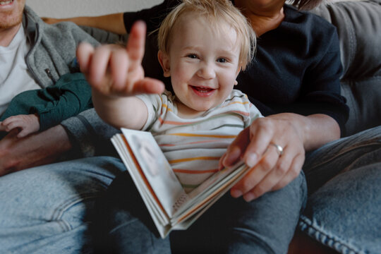 Candid family moment: happy toddler reading on parents' laps