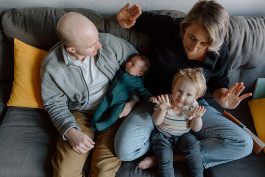 Candid family moment: parents with baby and toddler on couch
