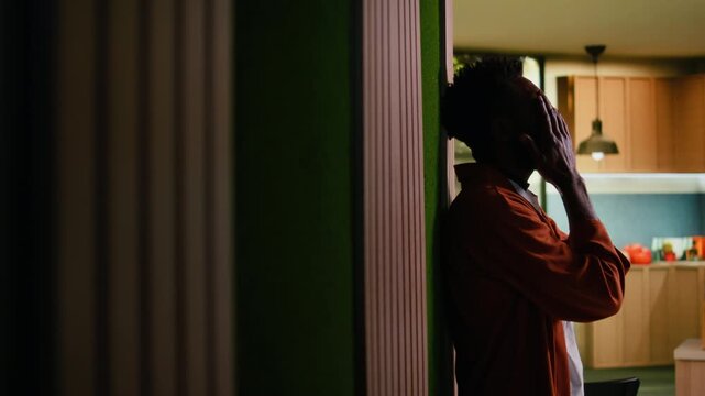 Distraught black man feels unfulfilled and disappointed in the hallway, lonely in sorrow. Unwell adult suffering from mental health issues, solitude and emotional pain, depressive mood.