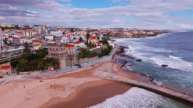 Aerial establishing shot of Atlantic coast with rolling waves and dramatic skyline. Praia do Tamariz, Cascais, Portugal