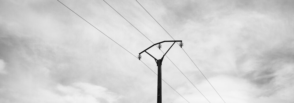 Electricity power line transmitting energy against cloudy sky