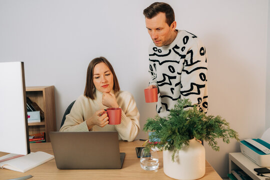 Partners looking at laptop screen during coffee break