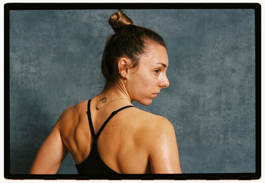 Woman poses with a focused expression against a blue backdrop