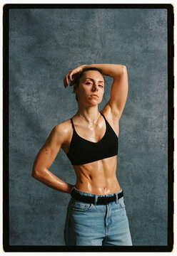 Model poses in black top and jeans against gray background