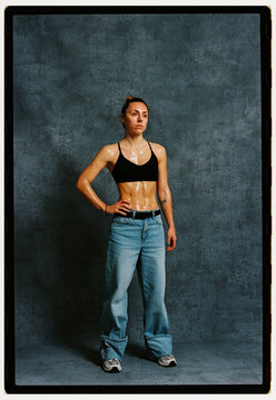Fitness model poses in studio with gray background and sweat