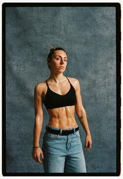 Model poses in a black top and blue jeans in studio setting
