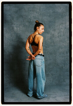 Young woman poses in casual clothing against a grey backdrop