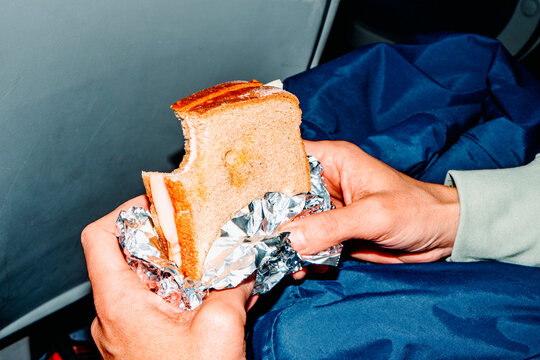 a man holds a bitten sandwich on public transport