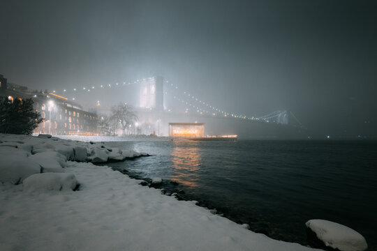 Brooklyn Bridge in Fog Above Snowy Dumbo Waterfront at Night