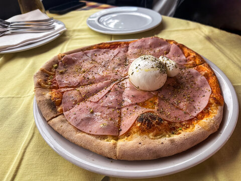 Close up of pizza with ham and egg on yellow tablecloth