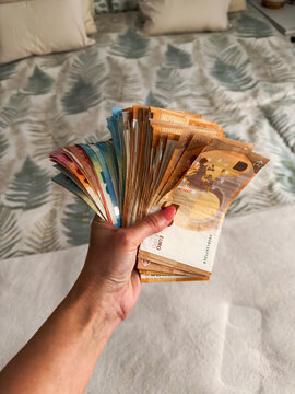 Woman holding euro banknotes in bedroom