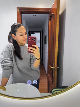 Woman taking bathroom mirror selfie at home