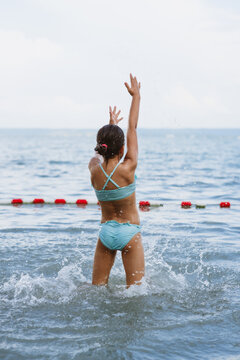 Young girl in the sea. She is splashing water and enjoying the view. 