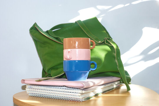 Colorful cups and notebooks are stacked on a table 