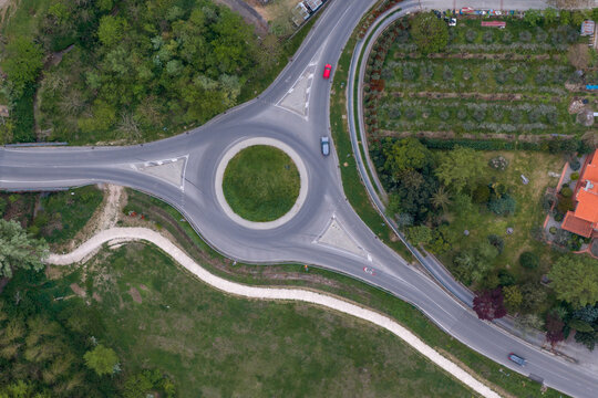 Aerial view of a road roundabout with cars surrounded by lush green trees and fields in Reggello, Tuscany, Italy.
