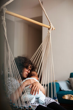 Mother Holding Baby in Hammock Chair at Home