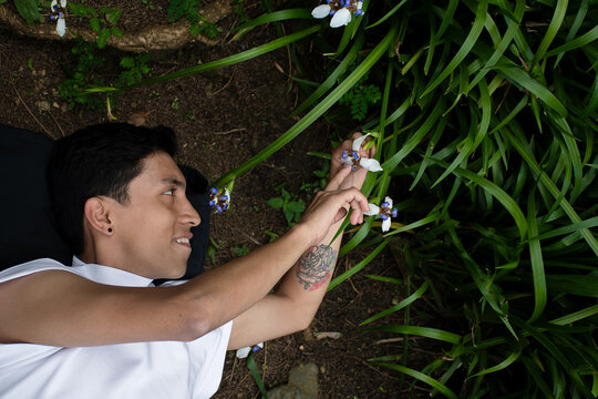 Young Man Explores Flowers While Lying on the Ground in Nature