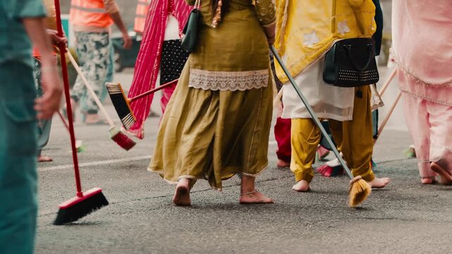 Indian women clean the street with brooms during the Vaisakhi holy procession