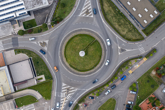 Aerial view of a traffic roundabout with cars driving through it, surrounded by industrial buildings and parking lots in Reggello, Tuscany, Italy.