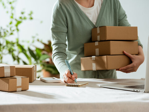 Small business owner organizing packages and taking notes for shipping