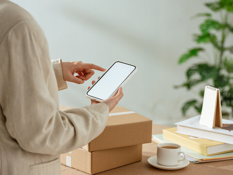 Person using smartphone to manage online orders and shipping boxes