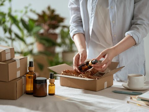 Hands carefully packing amber glass bottles and jars into a box