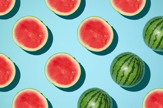 Vibrant watermelon halves and whole fruits arranged on a blue surface.
