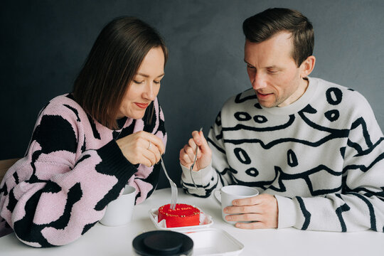 Couple in sweaters Eating Red Cake and Drinking Tea at Home