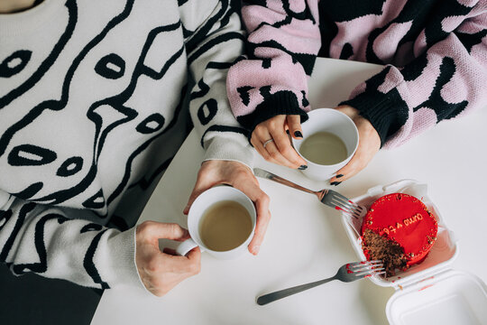 Anonymous couple having tea and cake indoors